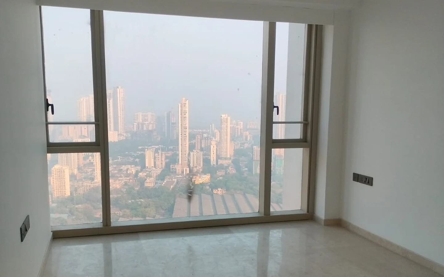 Bedroom with wide picture window and Mumbai skyline view on the 32nd floor at Lodha Park Tower Adrina, Worli
