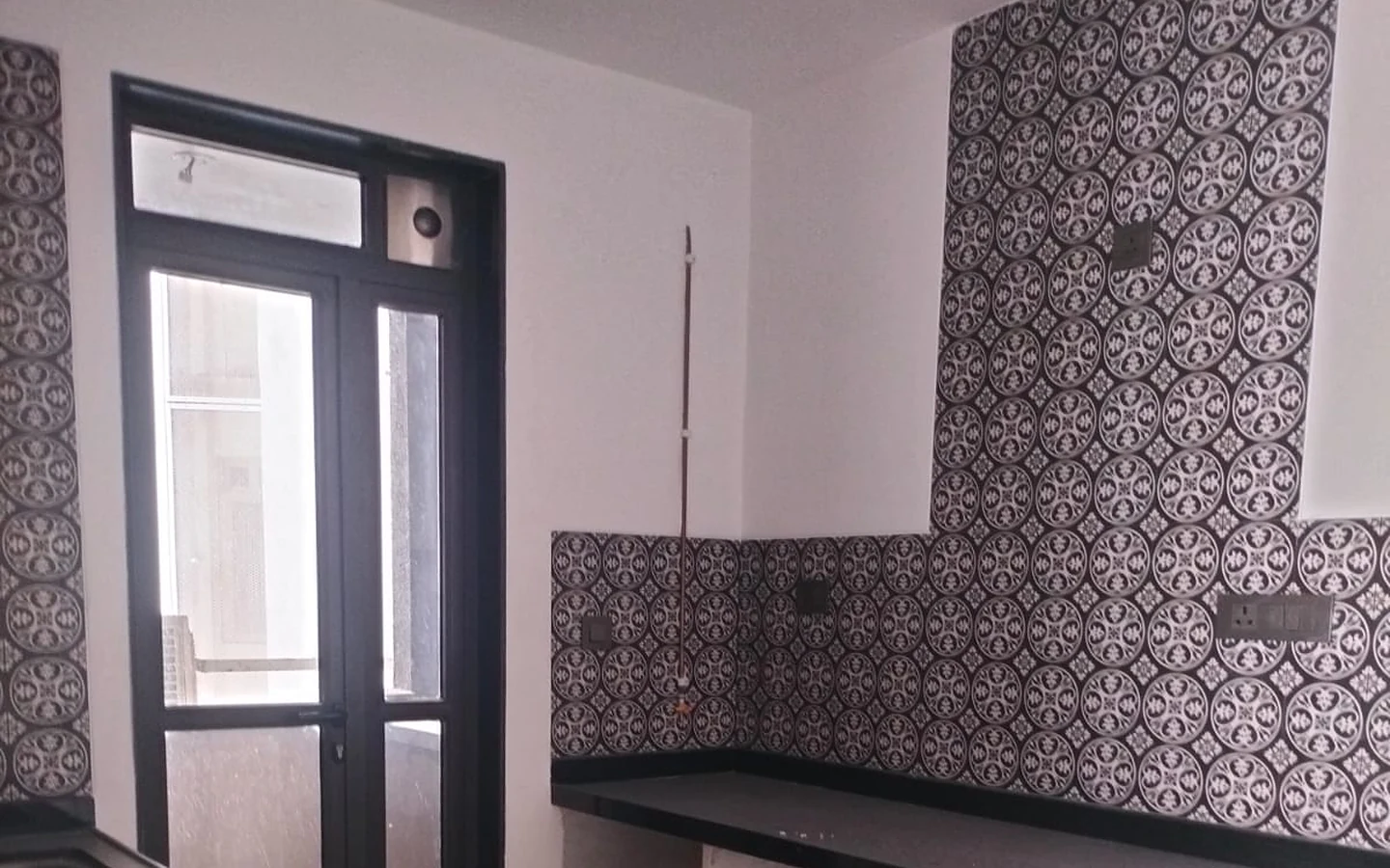 Kitchen with black granite counters, patterned tile backsplash and utility balcony door in 3 BHK at Lodha Park Tower Adrina, Worli