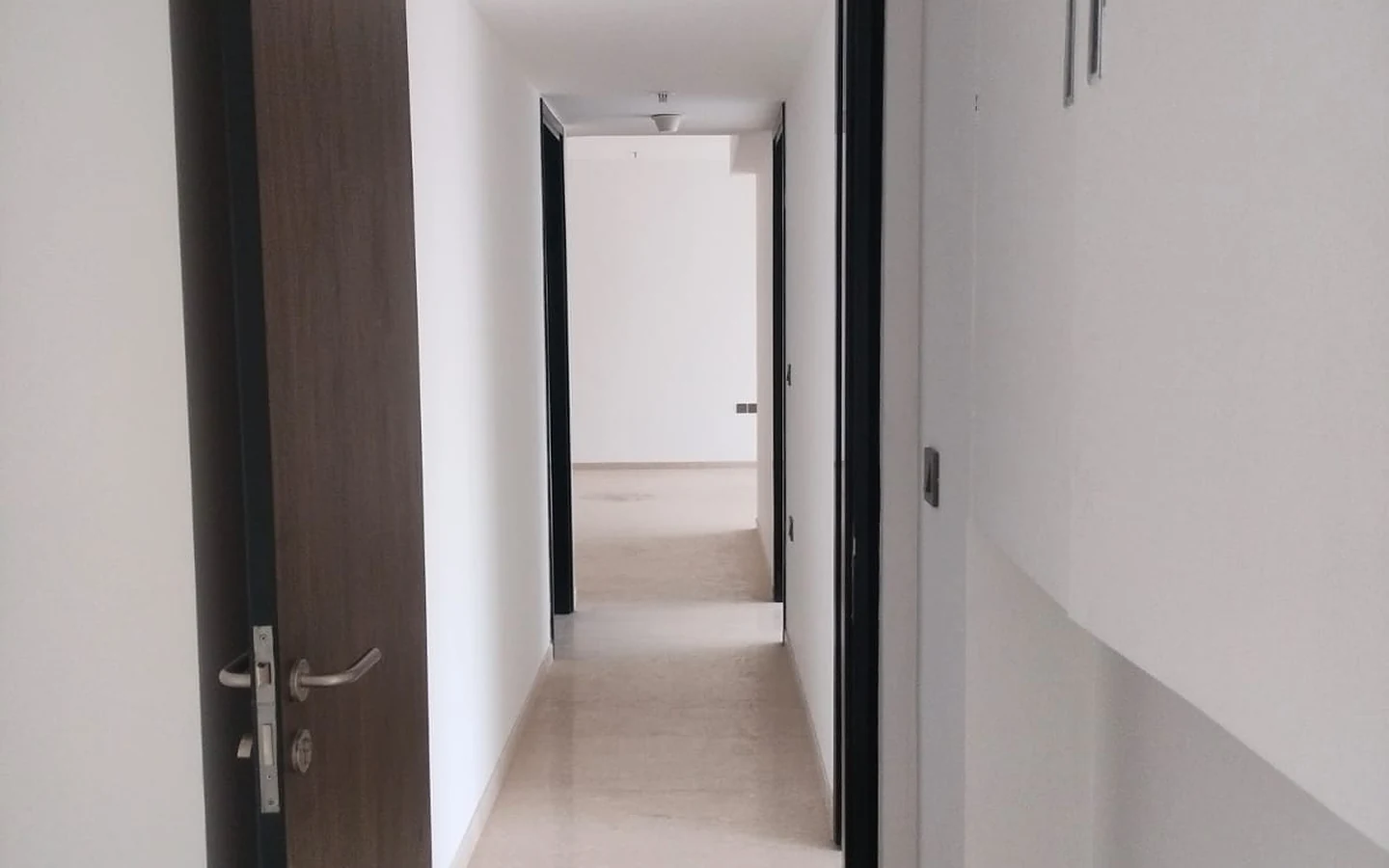 Passage leading to the bedrooms with marble flooring and wooden doors in 3 BHK at Lodha Park Tower Adrina, Worli