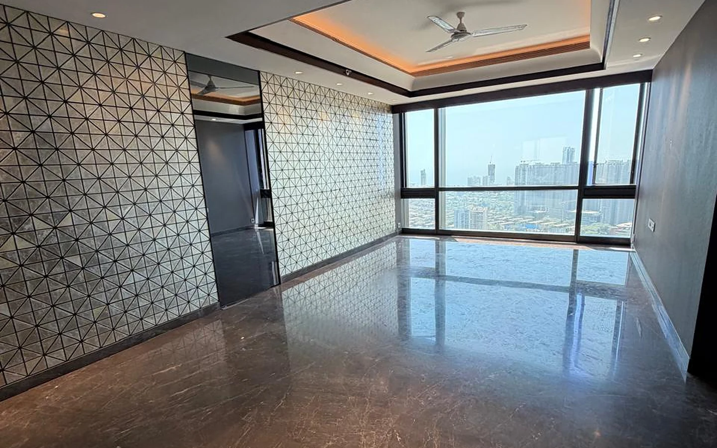 Living room with geometric mirror feature wall, cove-lit tray ceiling, Italian marble flooring and city view windows in 4 BHK at Lodha Trump Tower, Worli