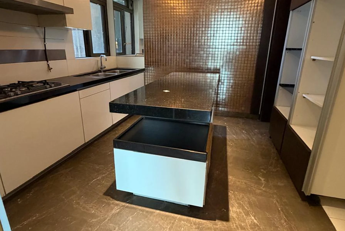 Modular kitchen with granite island counter, mosaic feature wall, cove lighting and built-in hob in 4 BHK at Lodha Trump Tower, Worli