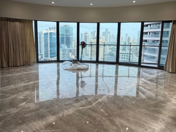 Spacious living room with curved floor-to-ceiling windows and panoramic Mumbai skyline view at Lodha World View, Lower Parel