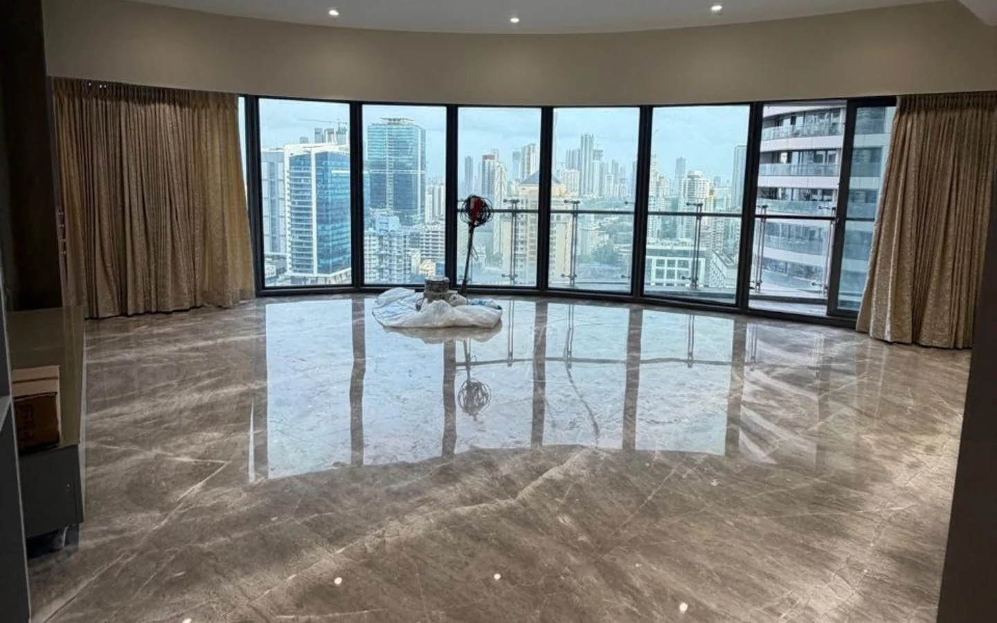 Spacious living room with curved floor-to-ceiling windows and panoramic Mumbai skyline view at Lodha World View, Lower Parel