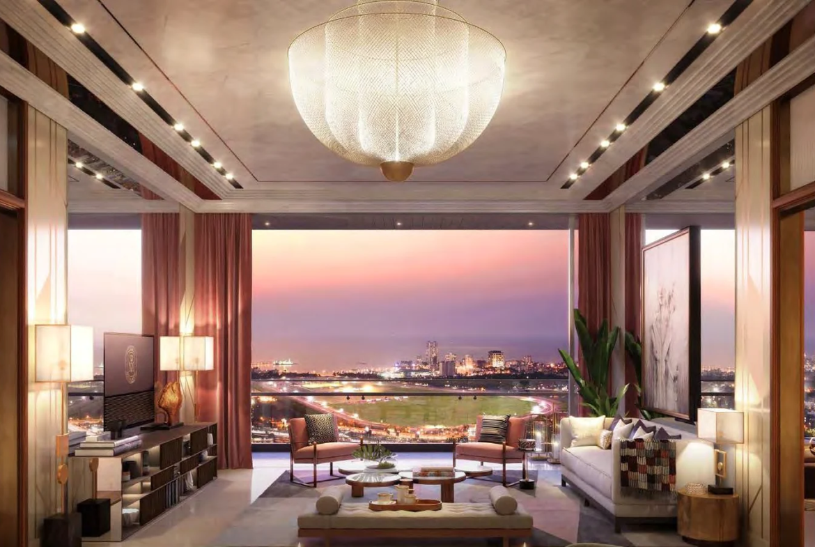 Sample living and dining room with chandelier and racecourse and sea view at dusk at Piramal Mahalaxmi, South Mumbai