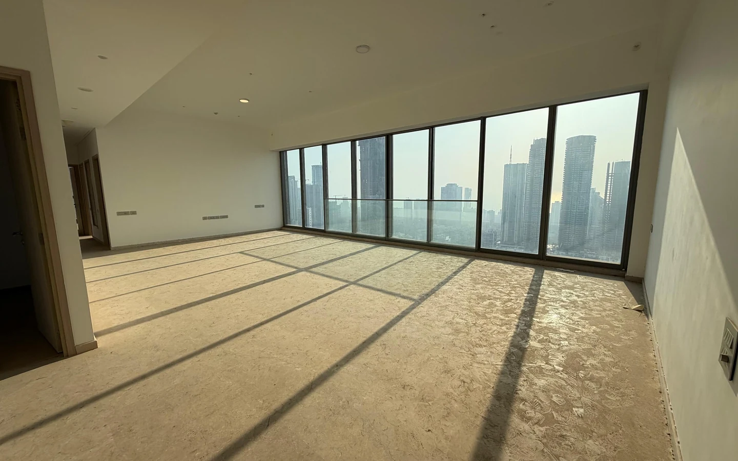 Spacious living room with full-width floor-to-ceiling glass windows and Mumbai skyline view in 5 BHK at Rustomjee Crown, Prabhadevi