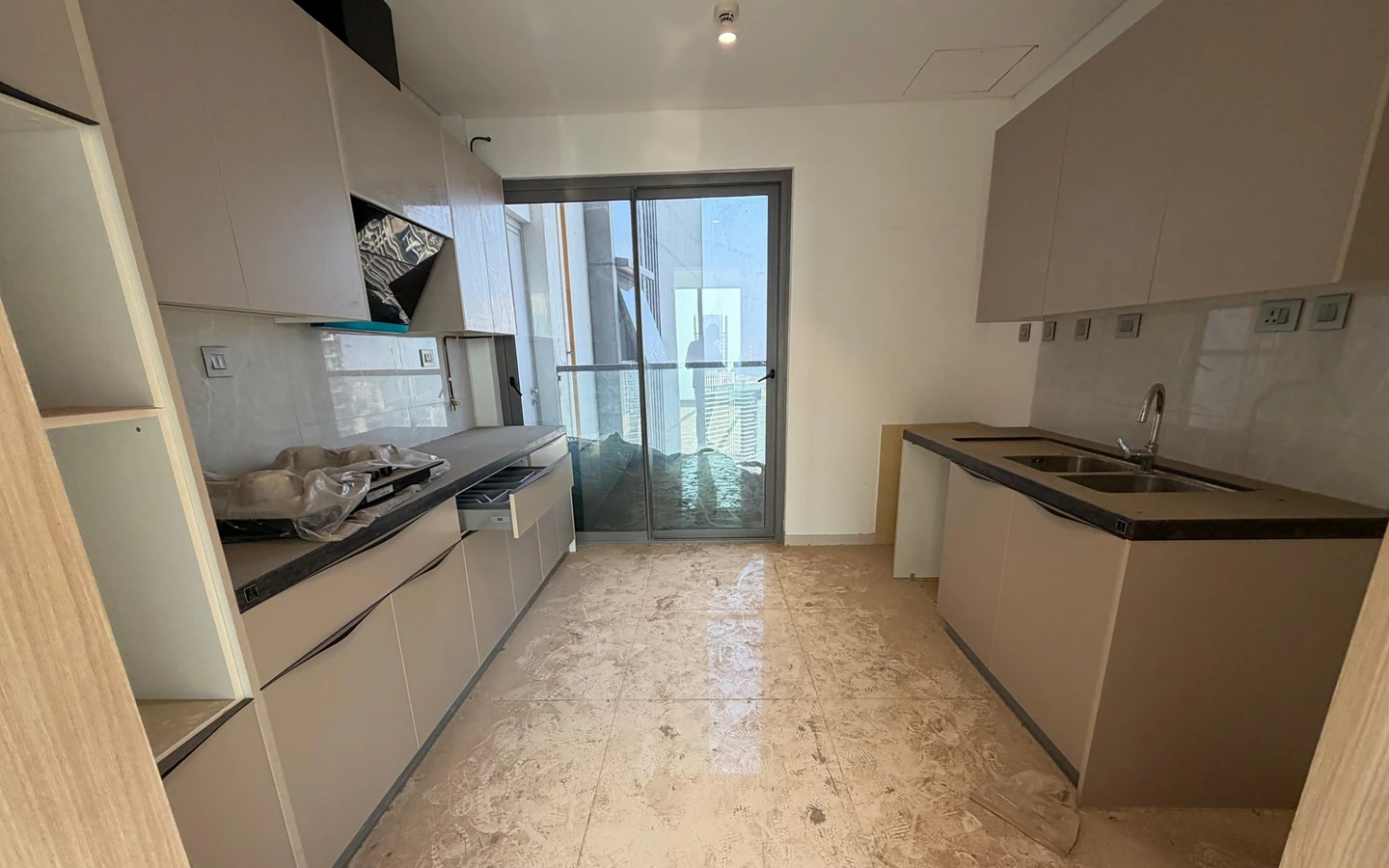 Modular kitchen with built-in cabinets, hob, chimney, double-bowl sink and balcony access in 5 BHK at Rustomjee Crown, Prabhadevi