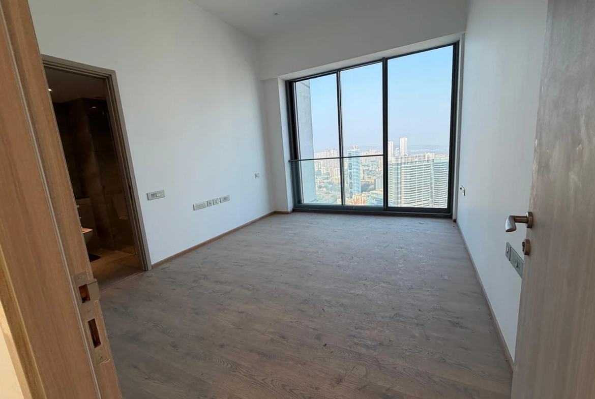 Master bedroom with wooden flooring, attached bathroom and floor-to-ceiling city view windows in 5 BHK at Rustomjee Crown, Prabhadevi