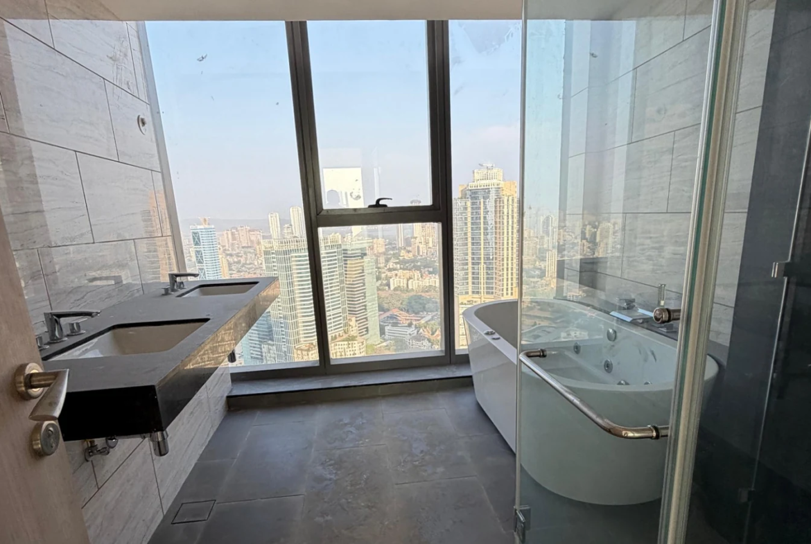 Master bathroom with jacuzzi bathtub, twin-sink vanity and full-height city view window at Rustomjee Crown, Prabhadevi