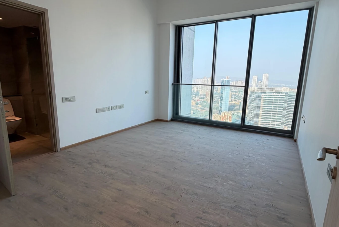 Bedroom with attached bathroom, wooden flooring and large city view window in 5 BHK at Rustomjee Crown, Prabhadevi