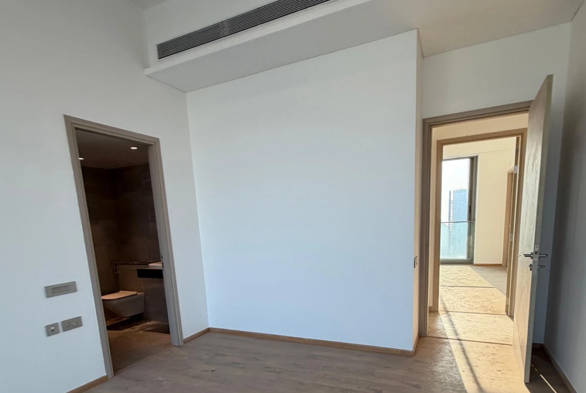 Bedroom with ducted air conditioning, wooden flooring and attached bathroom in 5 BHK at Rustomjee Crown, Prabhadevi