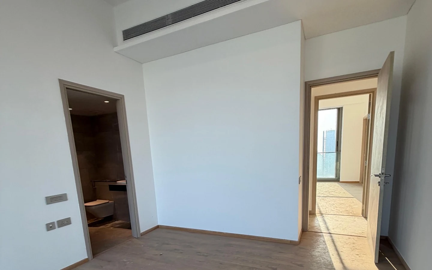 Bedroom with ducted air conditioning, wooden flooring and attached bathroom in 5 BHK at Rustomjee Crown, Prabhadevi